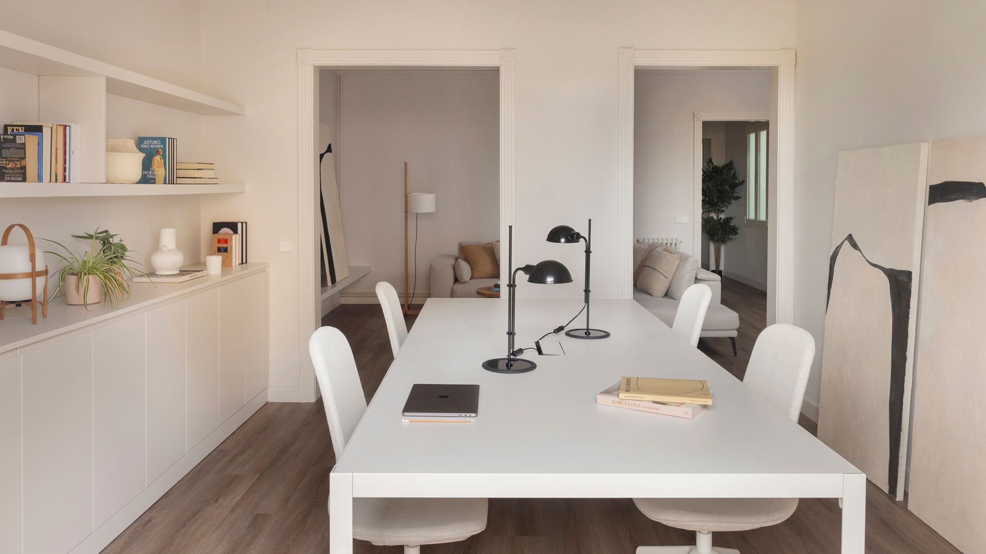 Despacho comunicado con el salón a través de dos huecos sin puertas, mesa XL blanca, lámparas de sobremesa 