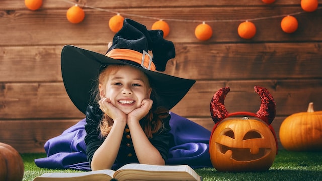Niña disfrazada de bruja con un libro de Halloween