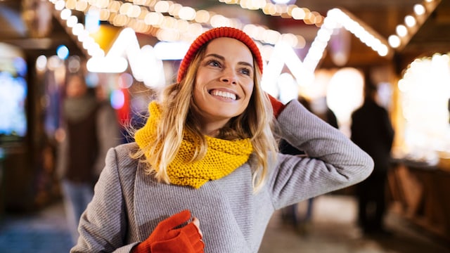 mujer abrigada paseando por un mercadillo navideño