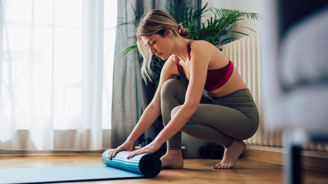 mujer extendiendo la esterilla para hacer pilates en casa