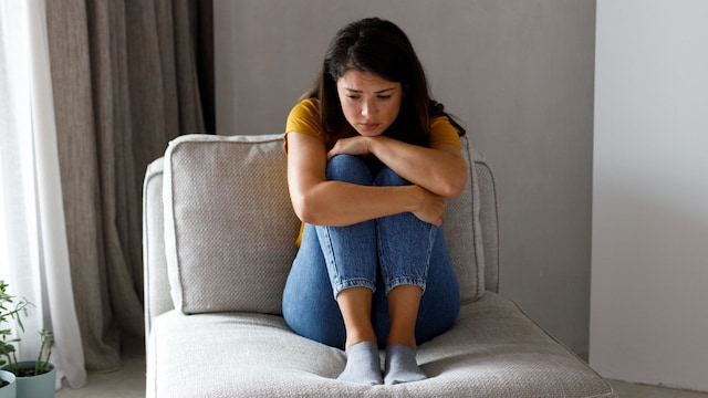 mujer preocupada sentada en el sofá