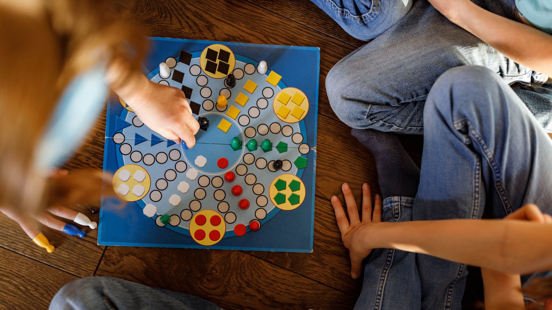 Juegos de mesa. Tablero sobre el suelo y un grupo de chicos alrededor. Vista cenital.