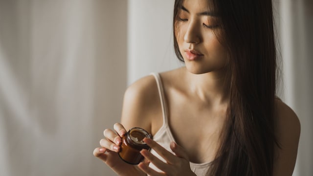 Mujer asiática aplicándose crema