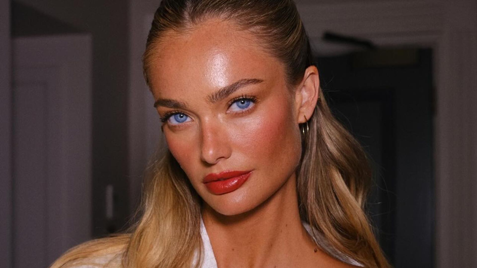 Modelo con pelo rubio, albornoz blanco y maquillaje en tonos rojizos