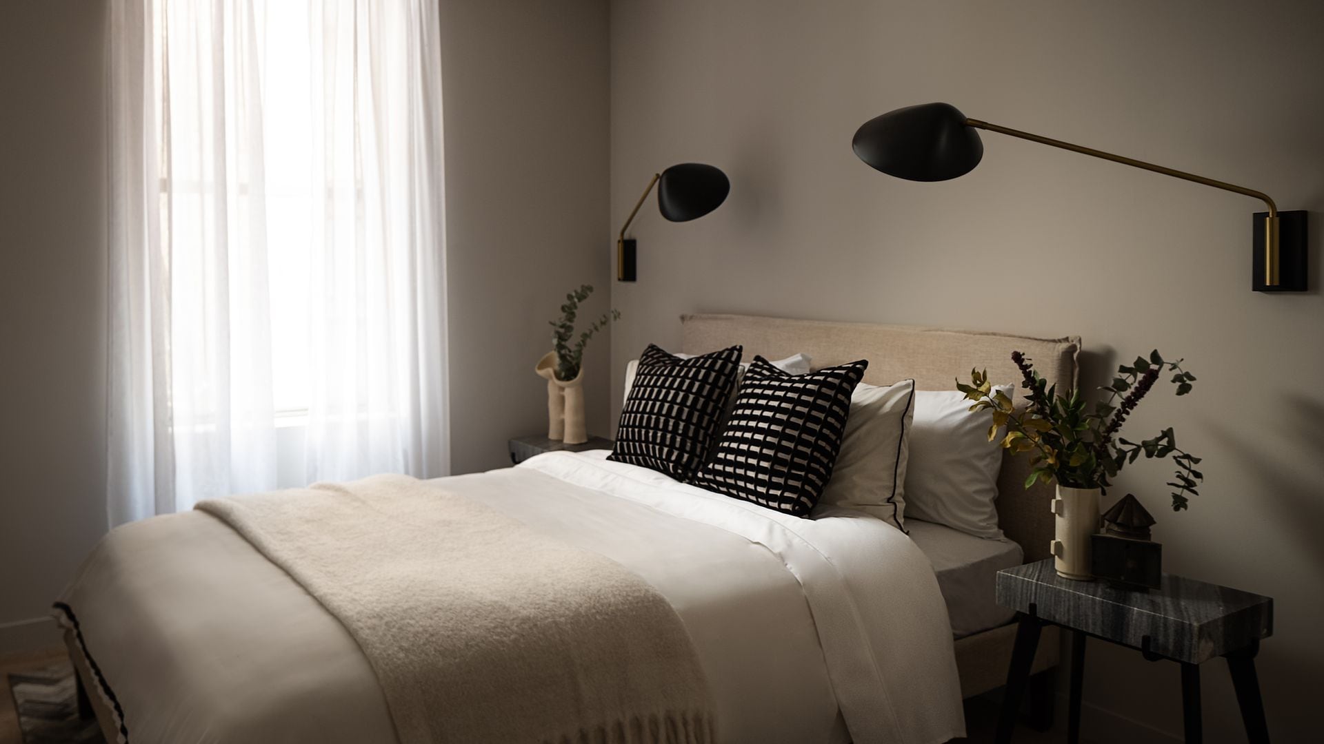 Dormitorio en tonos neutros con apliques negros de pared de gran tamaño