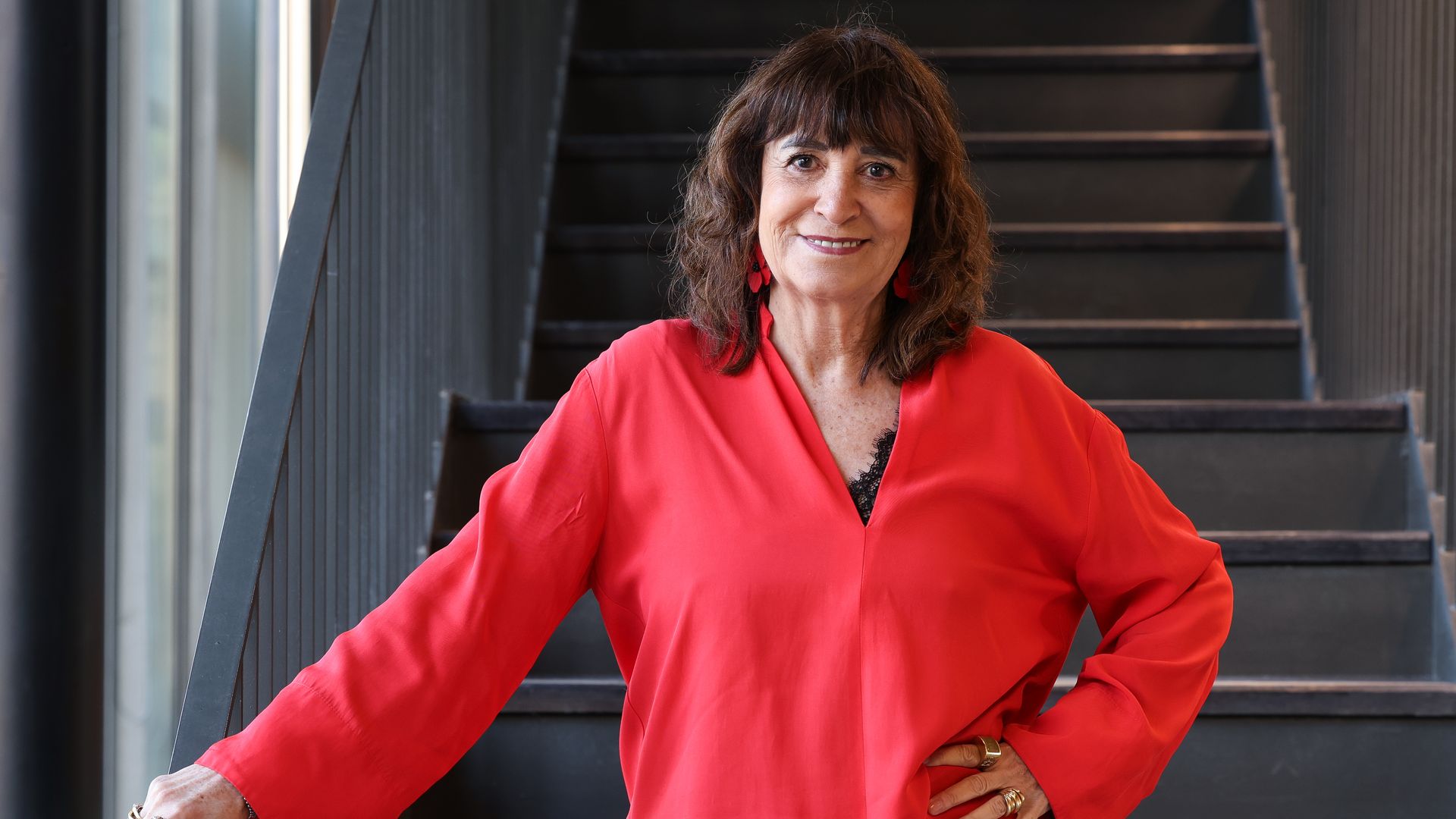 Rosa Montero posando frente a unas escaleras con camisa roja