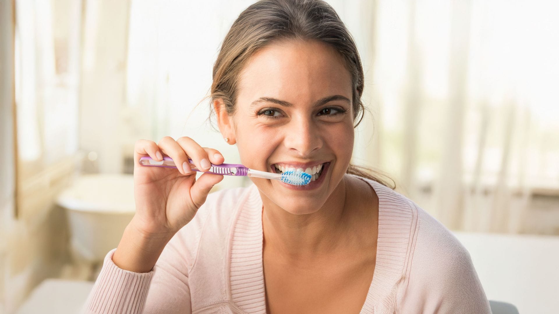 Una mujer cepillándose los dientes para tenerlos más blancos