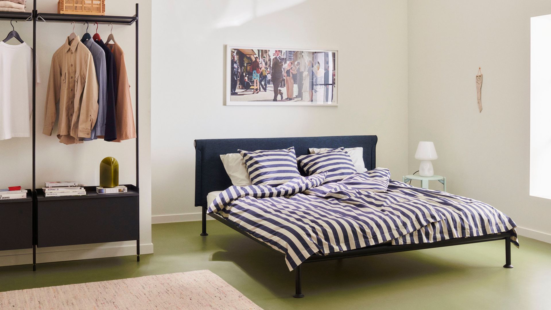 Dormitorio con cama negra, ropa de cama de rayas, armario abierto. alfombra