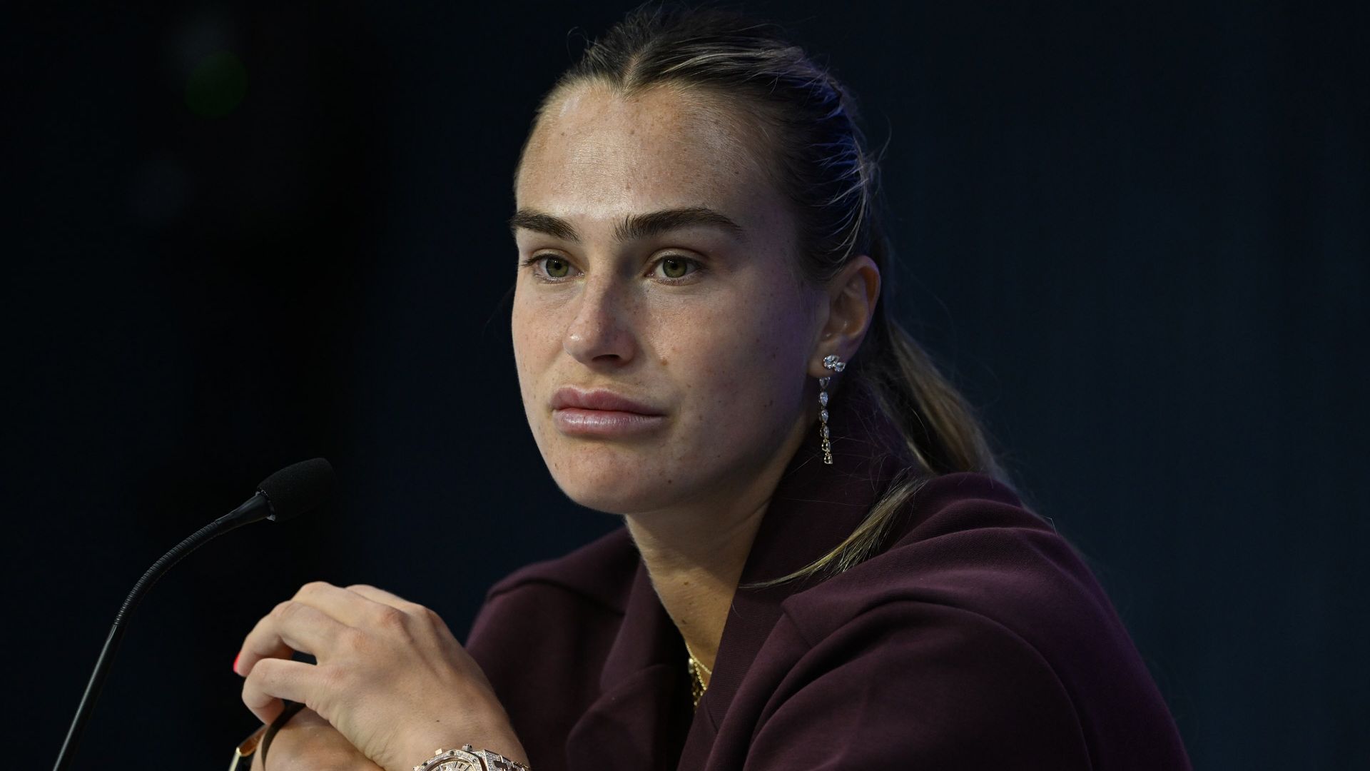 Aryna Sabalenka en una conferencia de prensa, con un reloj de oro y aretes.