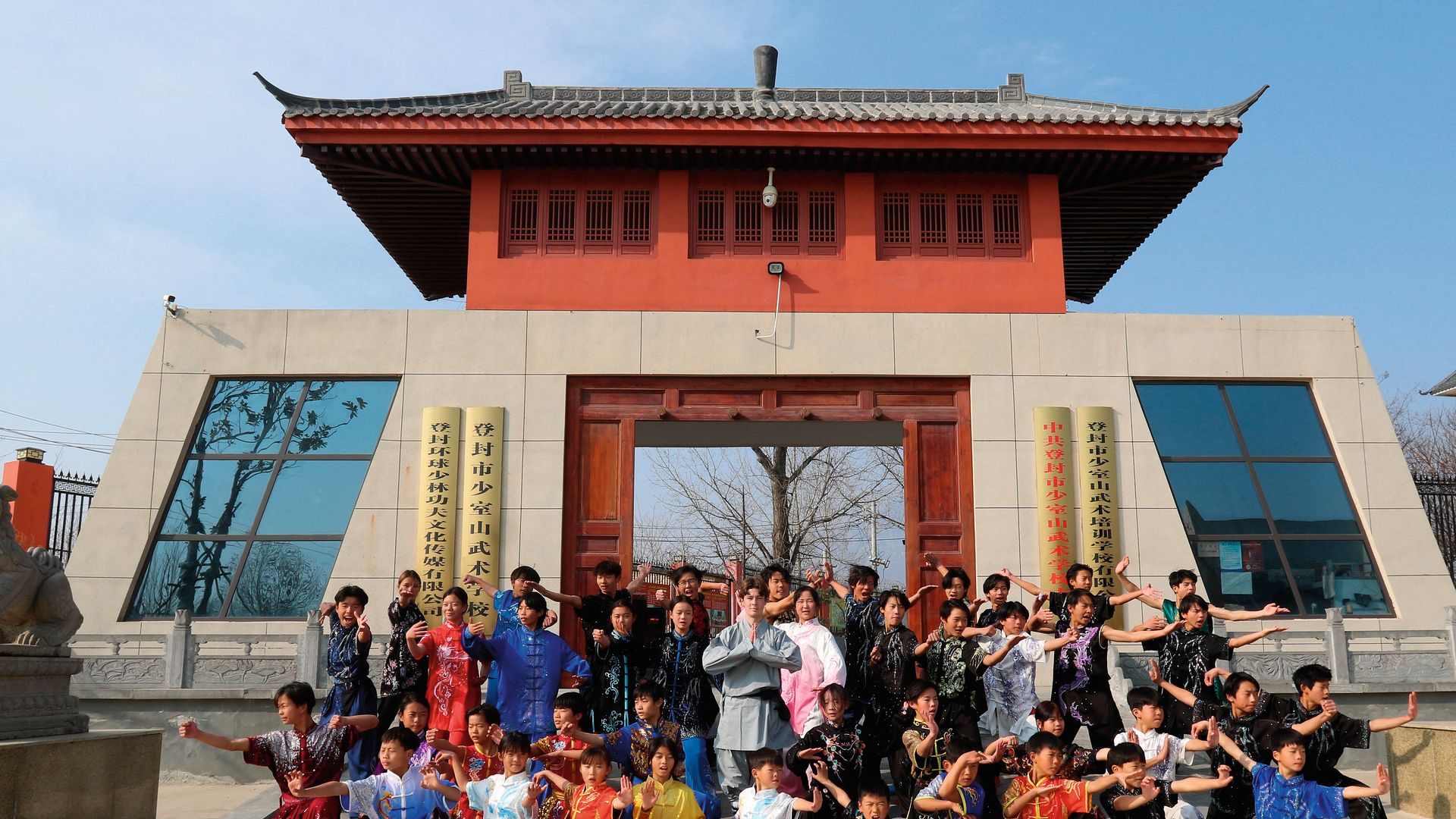 Grupo de personas en uniformes tradicionales frente a un edificio