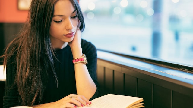 Mujer triste leyendo un libro en una cafetería