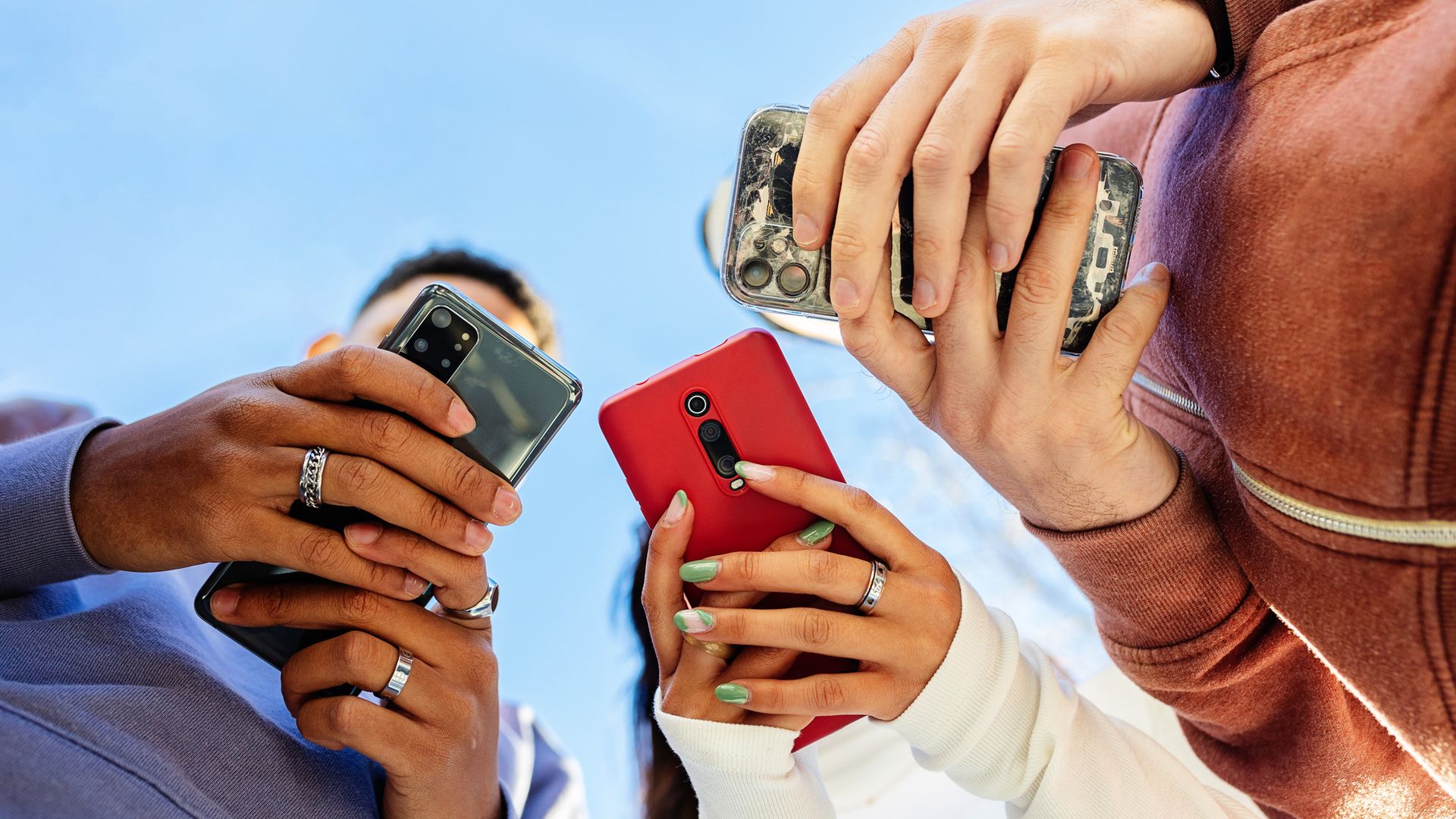 Tres chicos consultando su teléfono móvil 