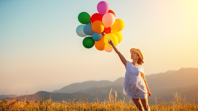 mujer feliz con globos de colores en el campo