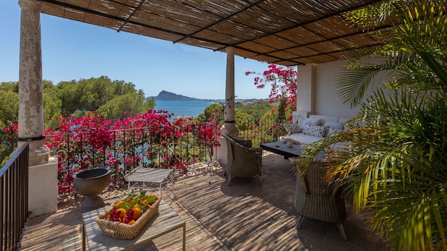 Terraza con pérgola de bambú, buganvilla en la barandilla, suelo de madera, sofá blanco, mesa con cesta con fruta, butacas de fibras vegetales