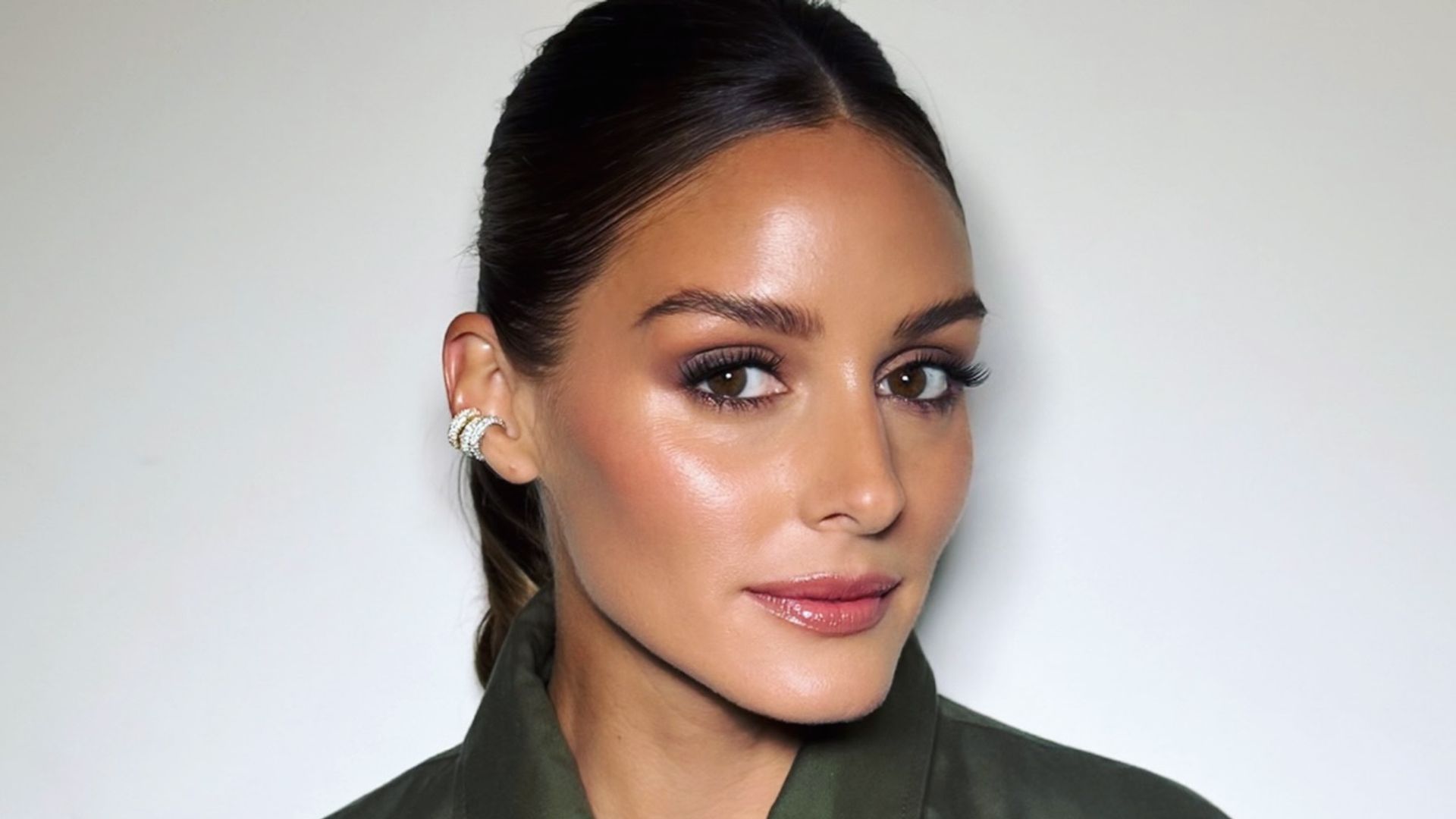 Olivia Palermo con maquillaje natural, chaqueta caqui de mangas estampadas y coleta pulida