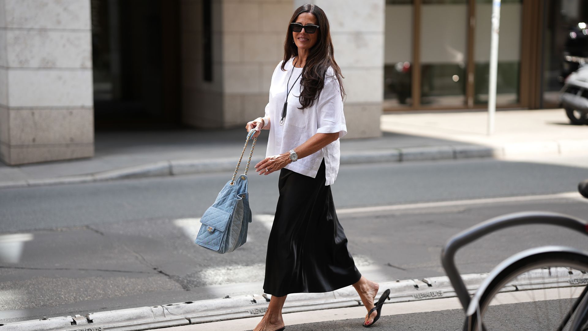 Angelika Hanel brilla en Frankfurt con falda midi negra de Arket, blusa oversized de Zara y bolso Chanel azul, combinando elegancia y estilo.