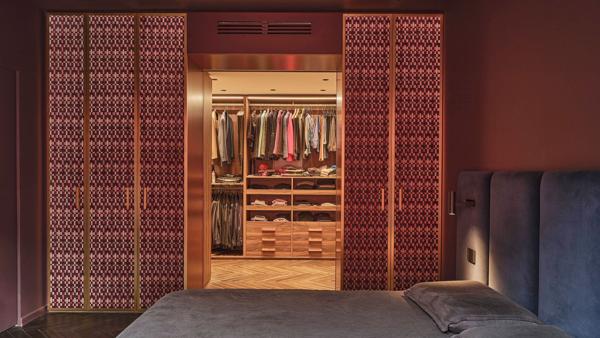 Dormitorio con vestidor con puertas de cristal, cabecero tapizado en azul 