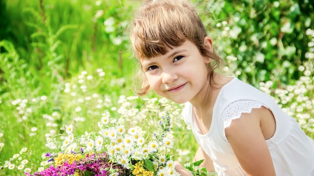 Niña con flores en el campo en primavera