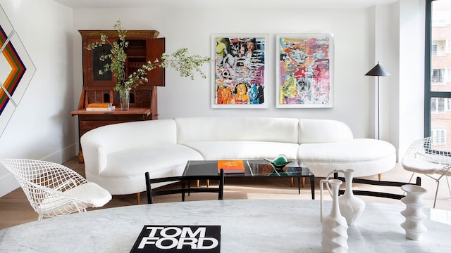 Salón con sofá blanco, cuadros de colores, secreter de madera oscura, mesa blanca redonda, lámpara de pie