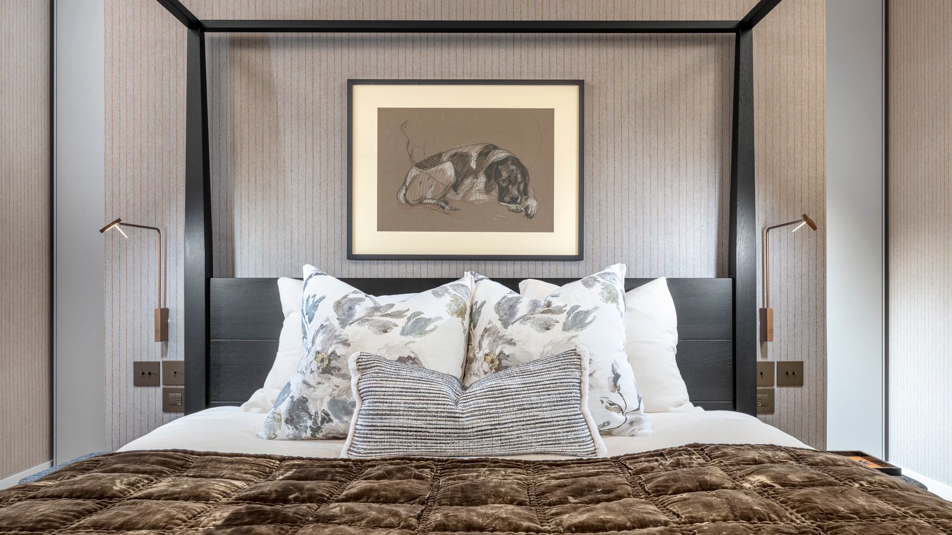 Dormitorio con cama con dosel negra, papel pintado gris, colcha marrón, cojines, cuadro en la pared del cabecero