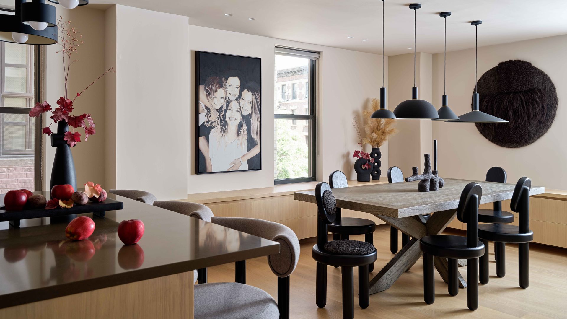 Comedor con mesa de comedor de madera, sillas negras, lámparas de techo negras, fotografía en blanco y negro en la pared, suelo de madera 
