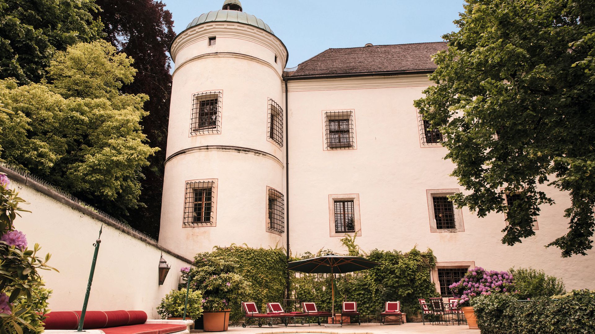Mansión con piscina, sillas rojas, y un gran edificio histórico al fondo