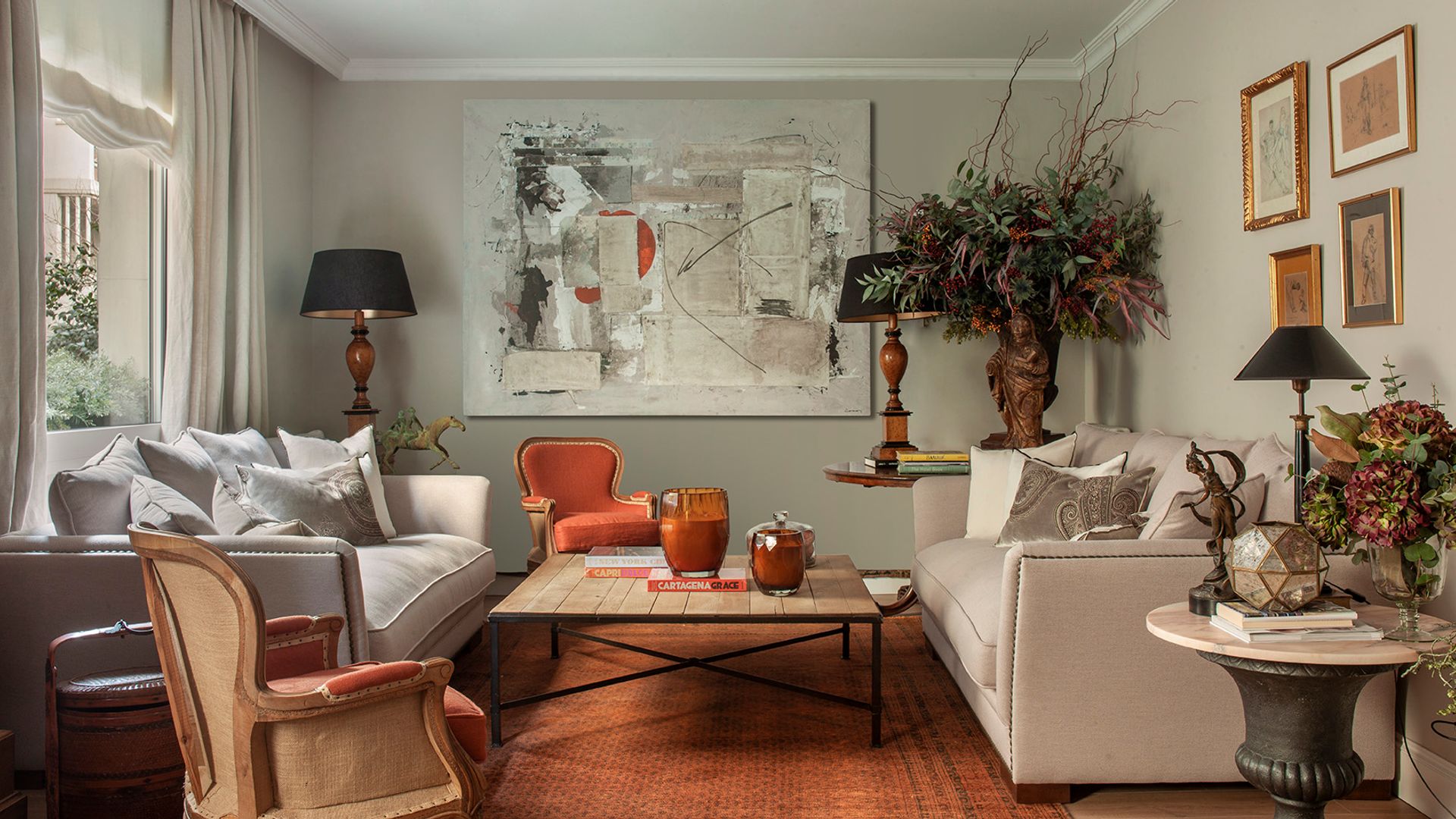 Salón clásico con alfombra marrón, sofás beige, molduras en el techo, sillas, lámparas de sobremesa negras, mesa de centro, mesas auxiliares, cortinas y estor