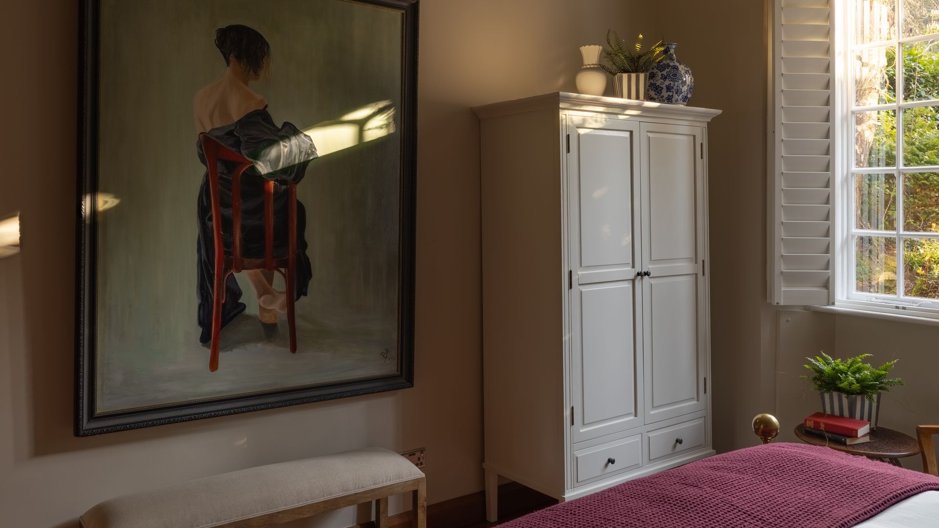 Dormitorio con ventanas mallorquinas, cuadro en la pared, armario exento, cuadro grande, banqueta descalzadora
