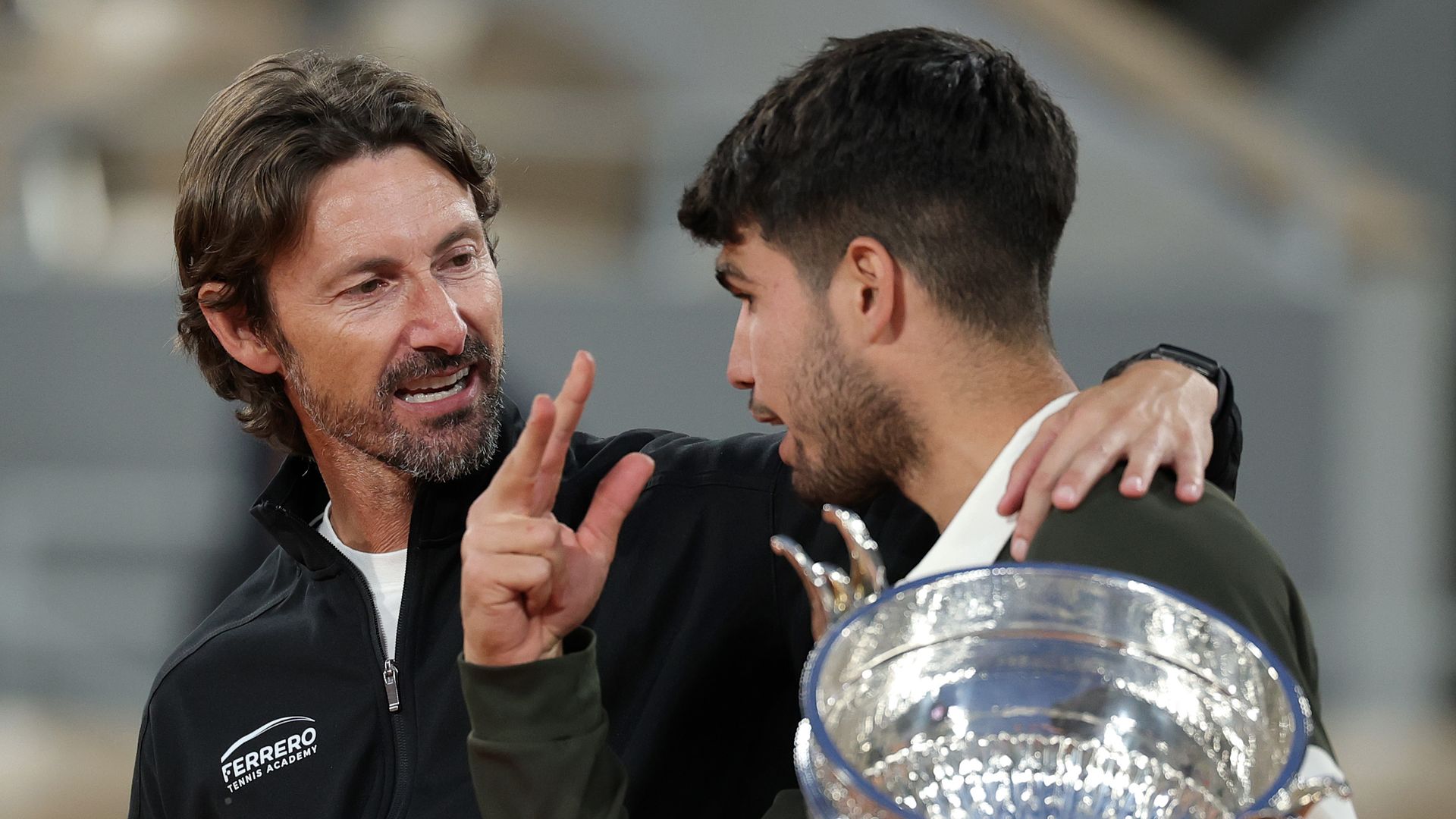 Carlos Alcaraz habla con su entrenador Juan Carlos Ferrero mientras sostiene el trofeo de la Copa de los Mosqueteros tras su victoria sobre Jannik Sinner el 8 de junio de 2025 en París, Francia. 