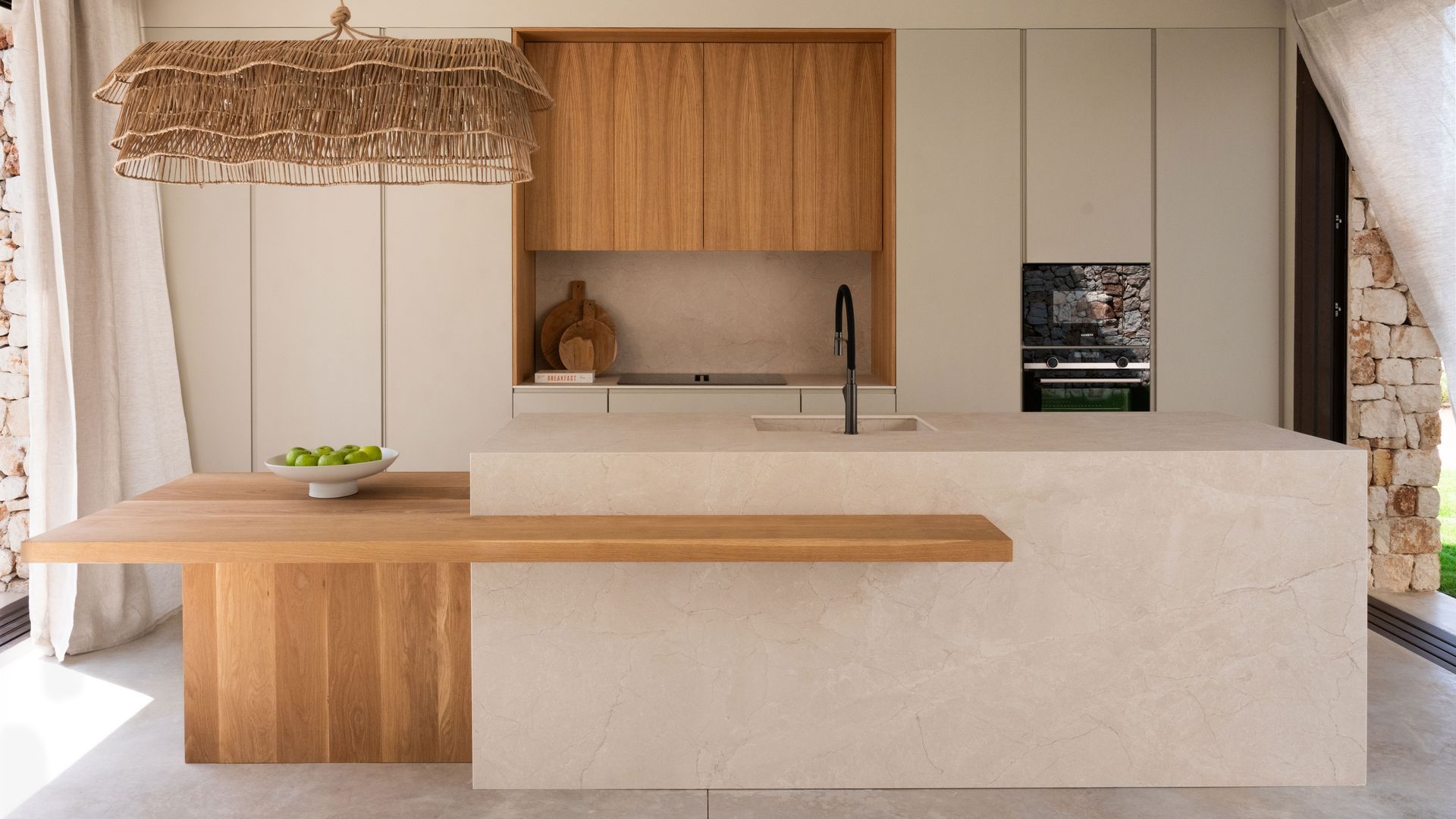 Cocina con isla con mesa de madera adosada, lámpara de techo de fibras vegetales 