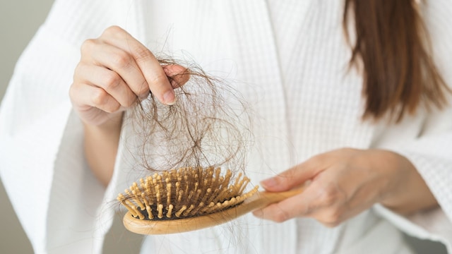 mujer recogiendo un mechón de cabello del cepillo del pelo
