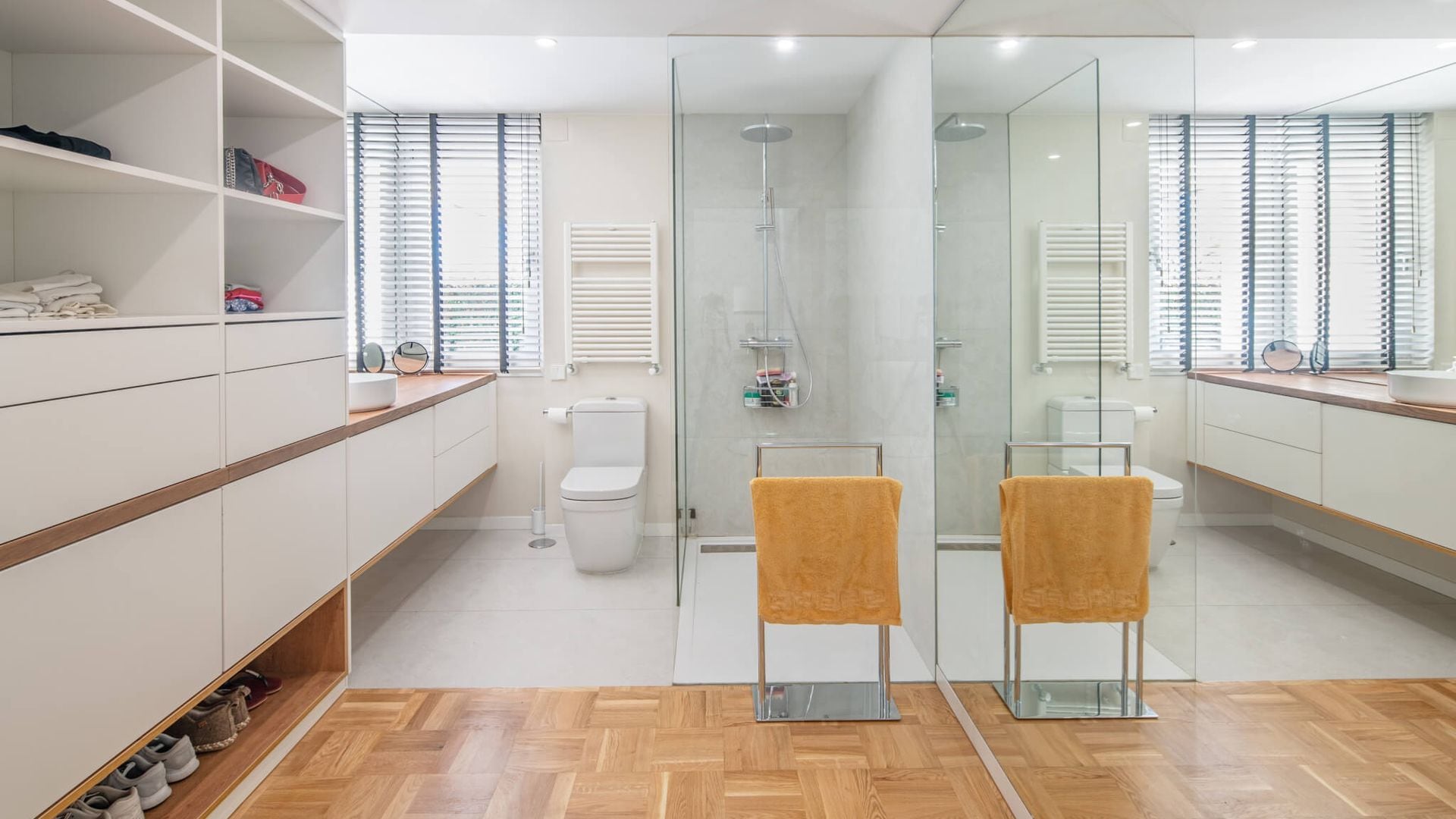 Baño con tabique de espejo, suelos de madera, vestidor, ducha con mampara, toallero de pie, radiador toallero