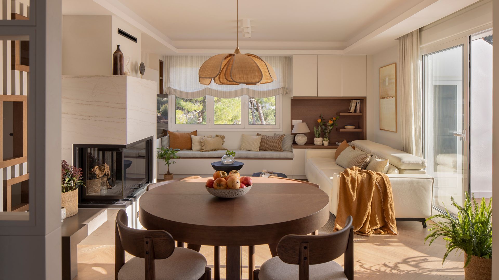 Salón comedor con chimenea moderna, mesa redonda de comedor de madera oscura, sofás blancos, mueble a medida