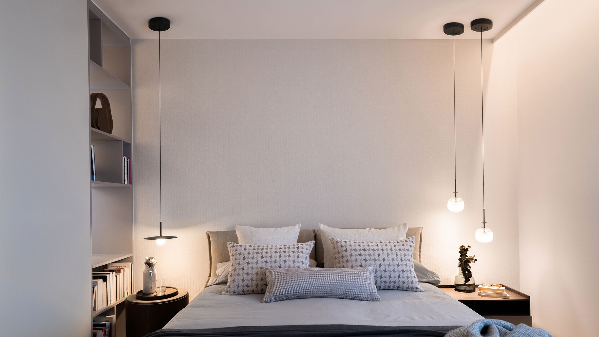 Dormitorio con lámparas de techo a ambos lados de la cama, luz perimetral en el techo, estantería 