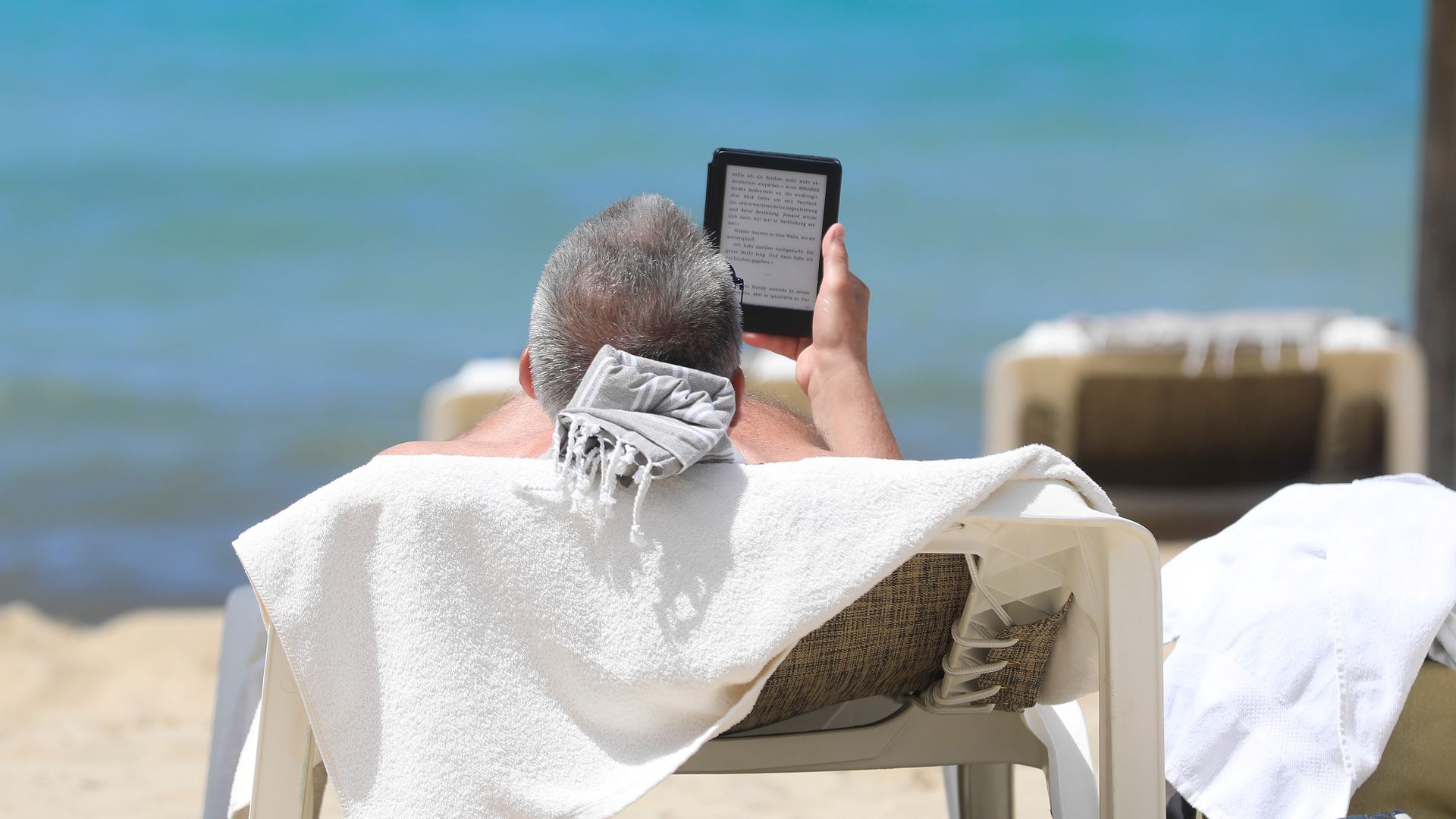 Hombre leyendo un ebook en la playa