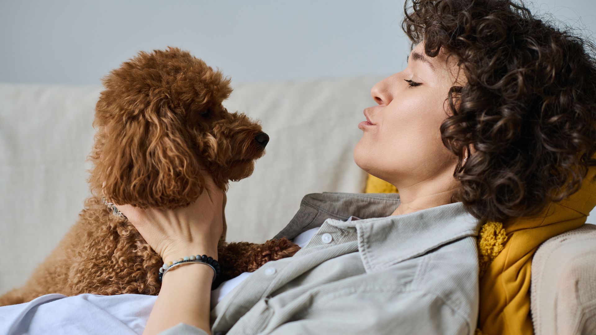 Mujer hablando con su perro mientras está tumbada en el sofá