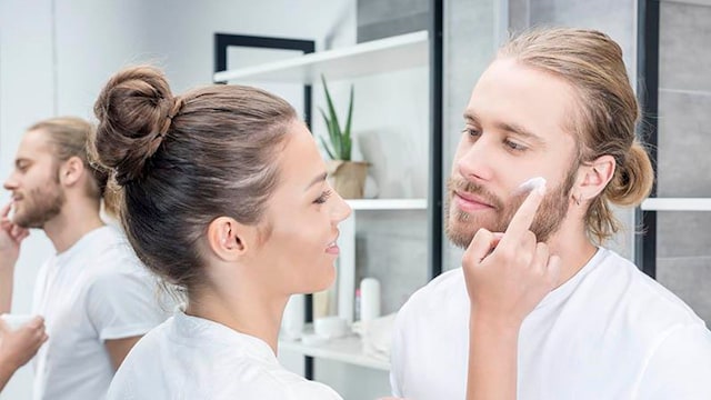 mujer aplicando crema facial a su esposo en el ba o