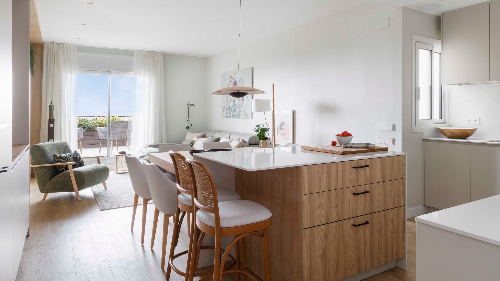 Cocina abierta al salón con isla de madera con zona de barra y de comedor a continuación de la barra 