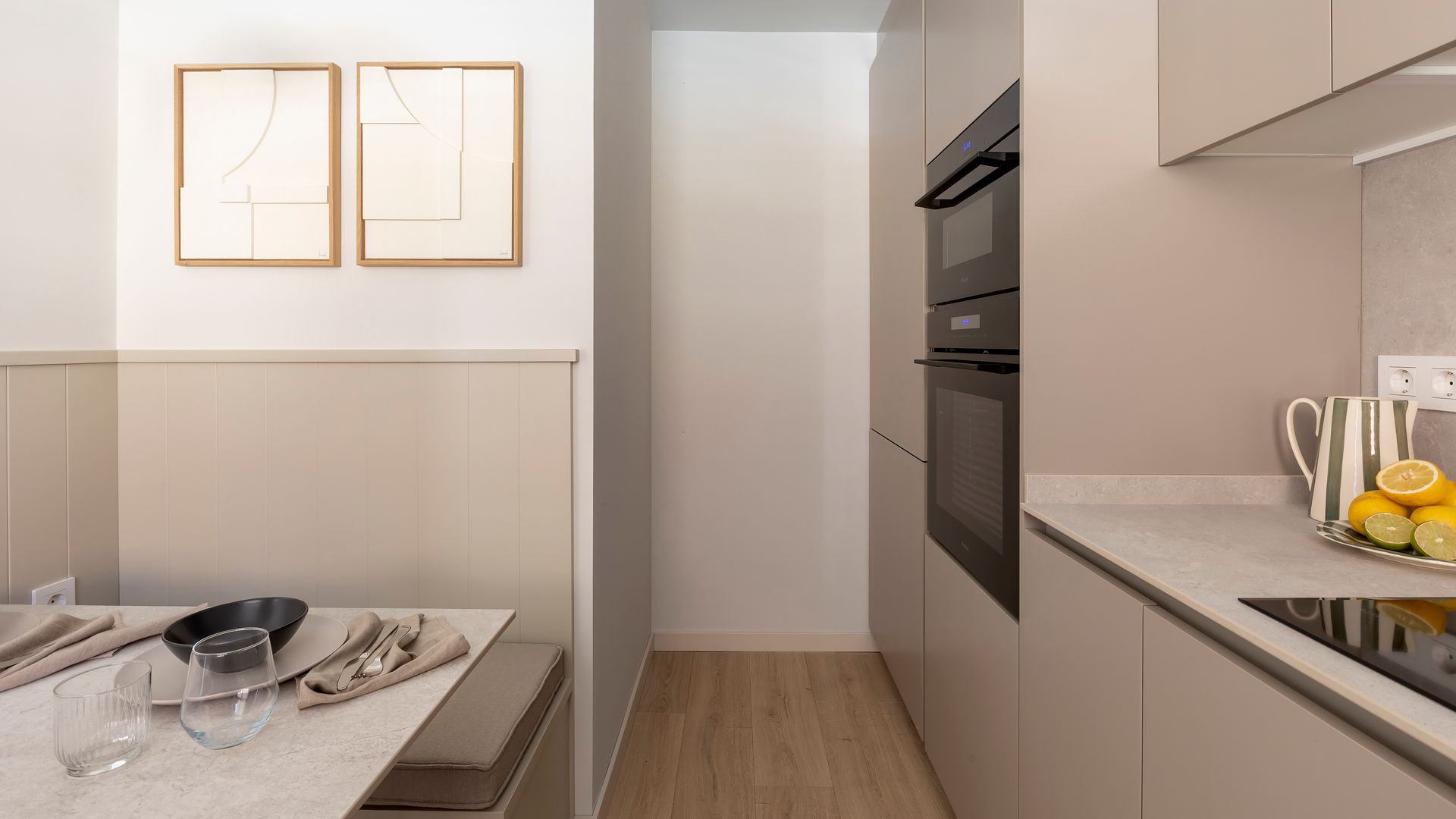 Cocina en beige con office, muebles hasta el techo, banco, cuadros en la pared