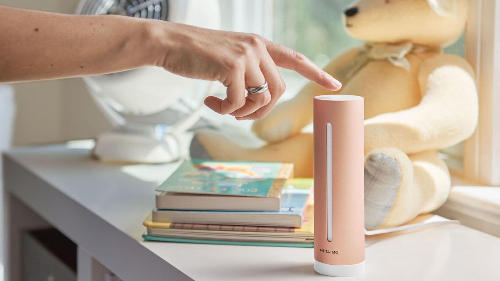 Netatmo Smart Indoor en la estantería de una habitación infantil. Una mujer lo está poniendo en marcha.