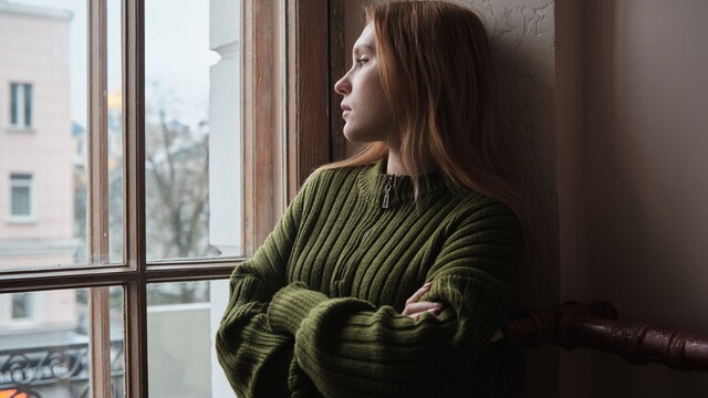 mujer preocupada mirando por la ventana