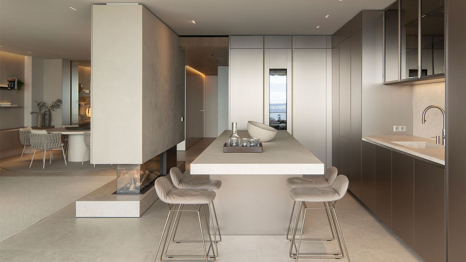 Cocina abierta al comedor con isla, muebles de madera, chimenea en tabique y focos empotrados