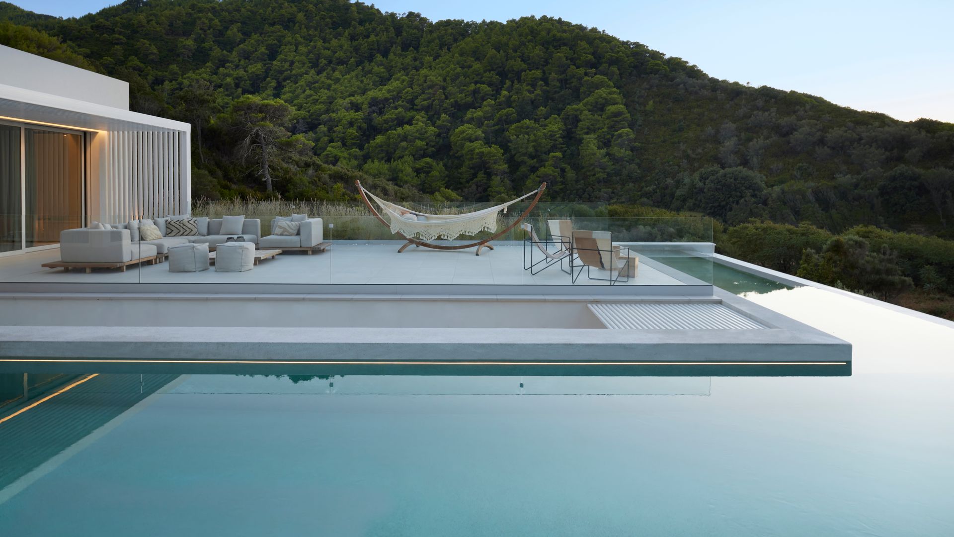 Chill out junto a la piscina con hamaca y zona de estar con sofás 