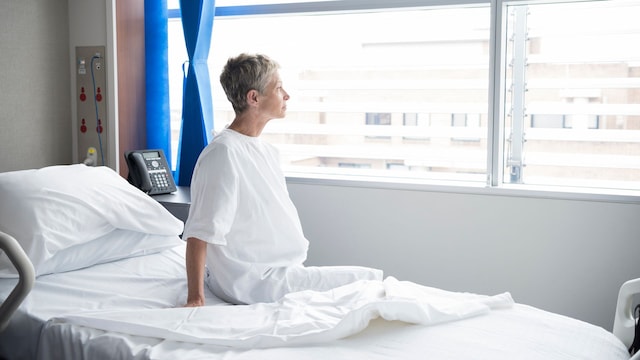 mujer sentada en una cama de hospital mirando por la ventana