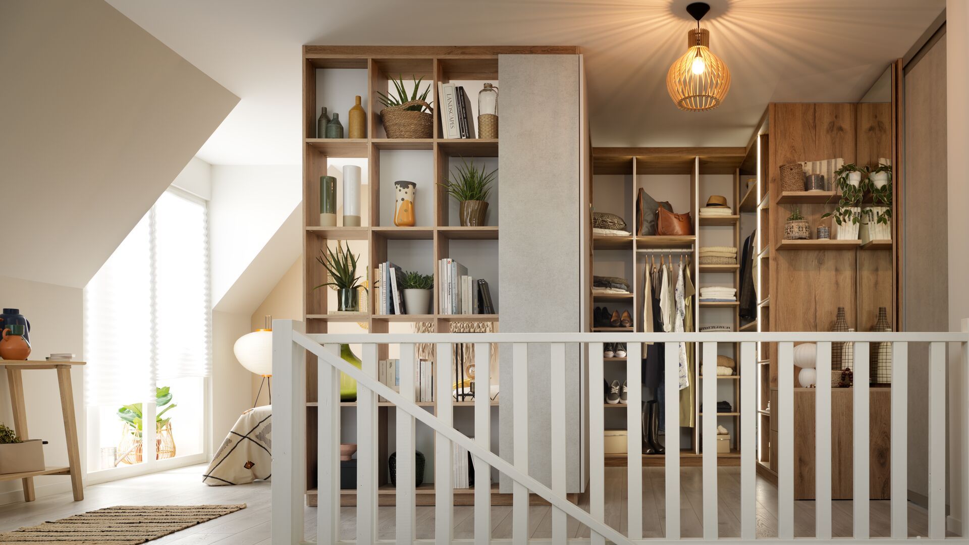 Buhardilla con vestidor con zona de armario, estantería con libros y adornos, barandilla blanca,  techo abuhardillado 