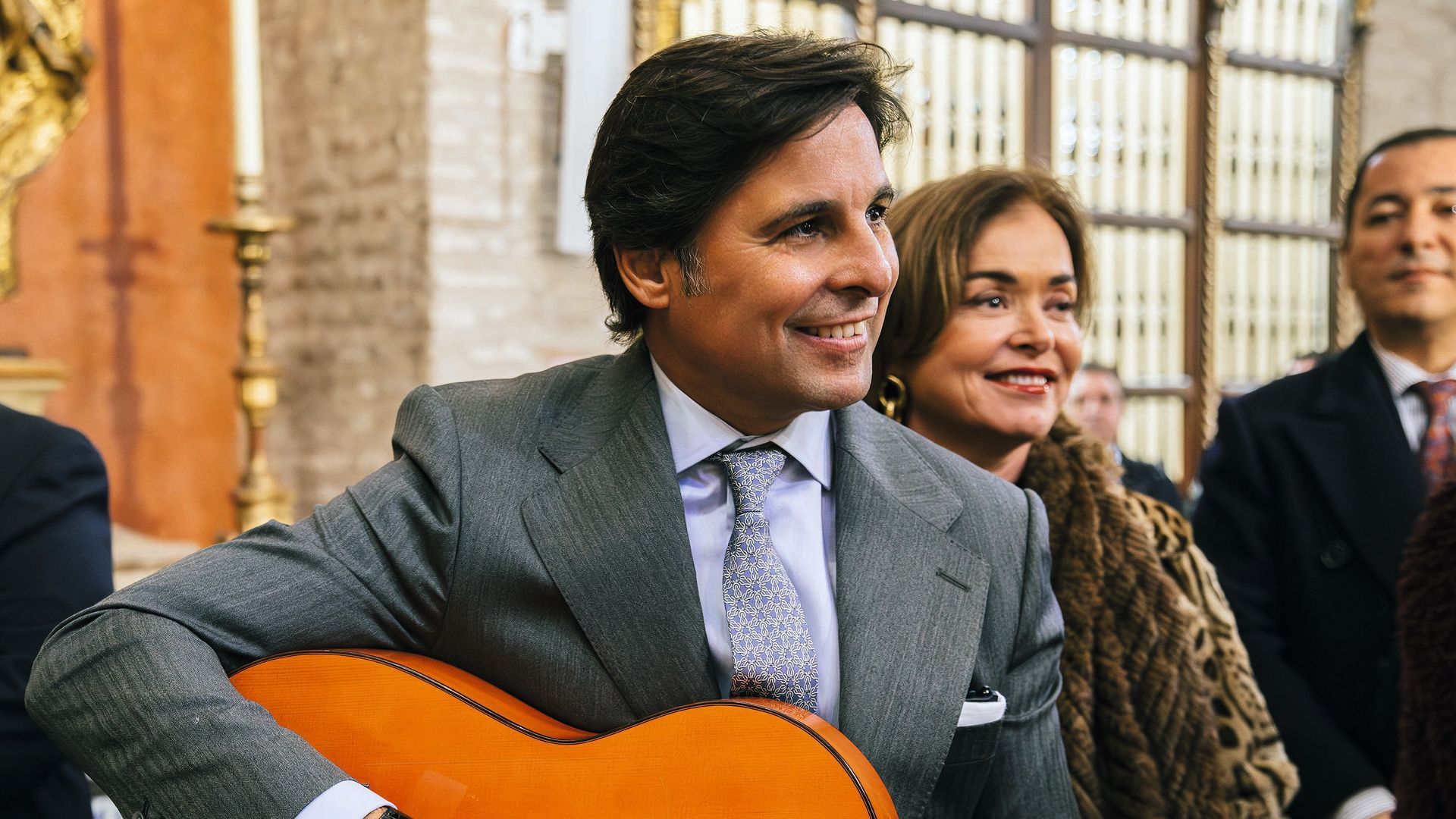 Francisco Rivera en la iglesia toca la guitarra con traje y corbata