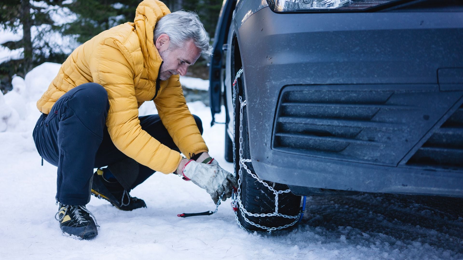 Un hombre colocando las cadenas a su coche