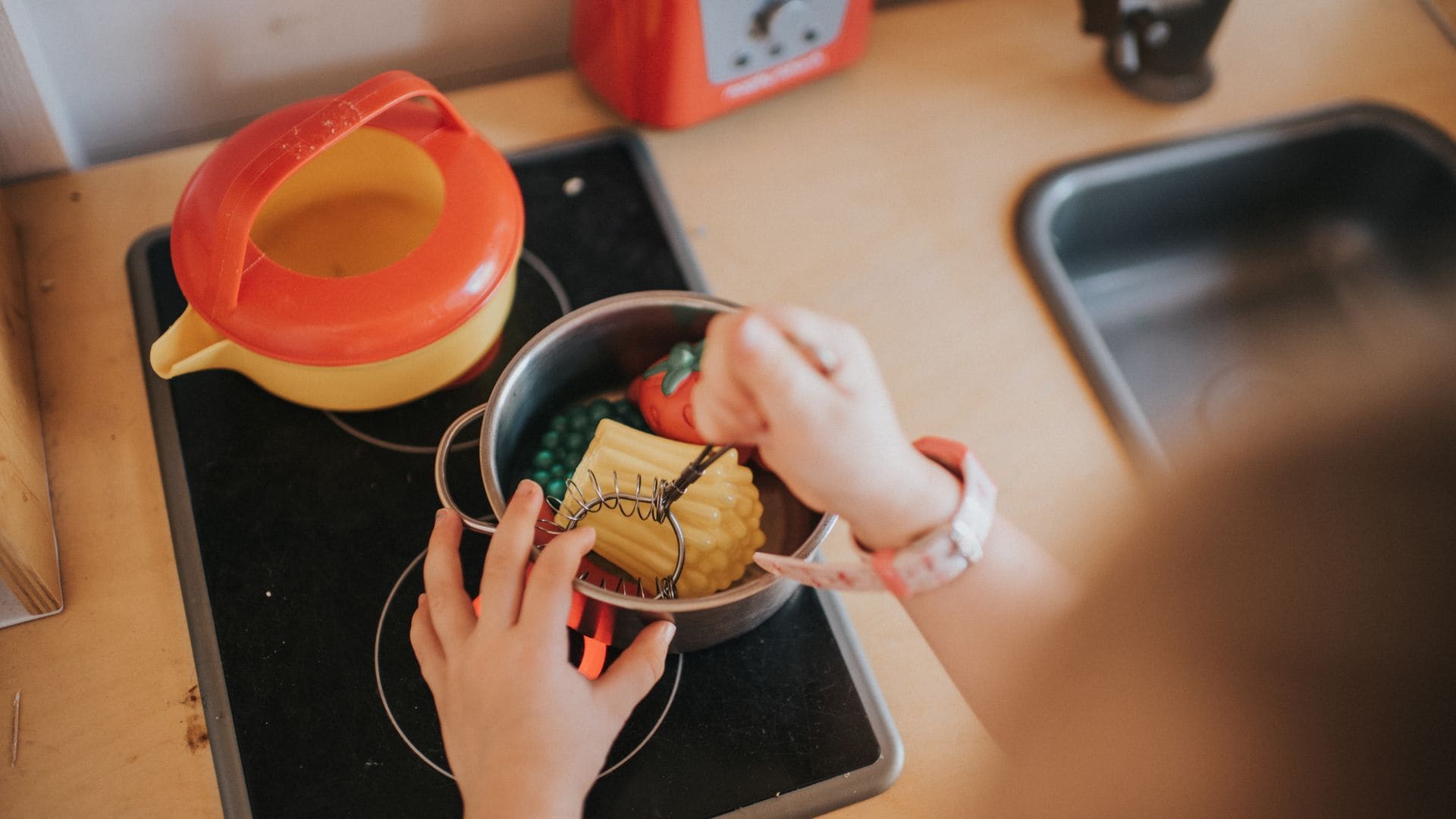 Niño cocinita de juguete haciendo una comida en una cazuela. Plano detalle de las manos.