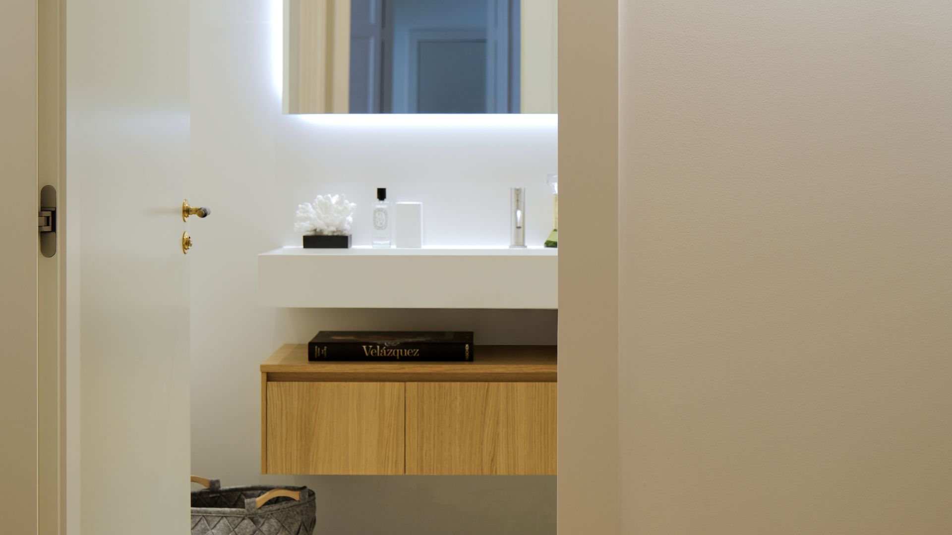 Baño con mueble volado de madera y espejo retroiluminado