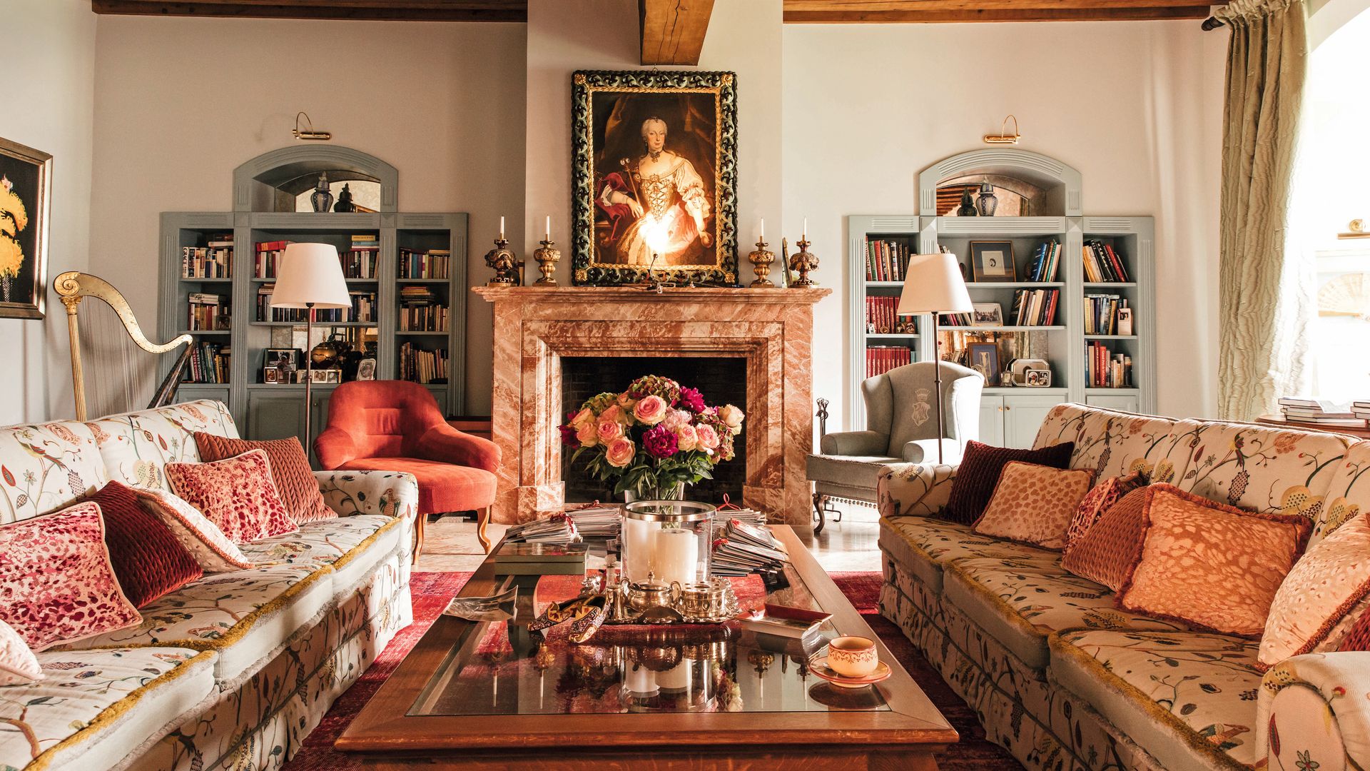 Sala de estar elegante con dos sofás florales, chimenea y pintura clásica en la pared